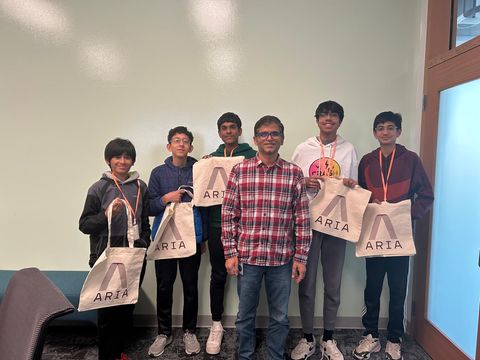 The team with a Meta researcher, each holding a Project Aria tote bag after their visit.