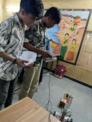 Two students at Madinaguda Government School driving the team's FTC robot across a classroom floor.
