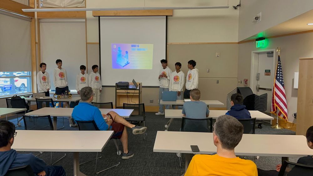 The team presenting a slideshow about robotics to an audience seated in a Redmond Library meeting room.