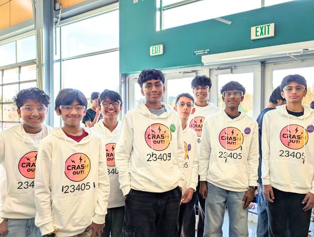 The Crash Out! team in matching white 23405 hoodies, standing together at a competition venue.
