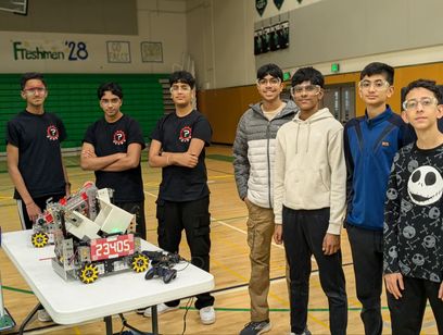 Crash Out members standing with team 23404 Bot Not Found and both robots in a school gym.