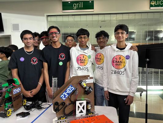 Crash Out members with another FTC team behind a table holding both of their robots at a competition.